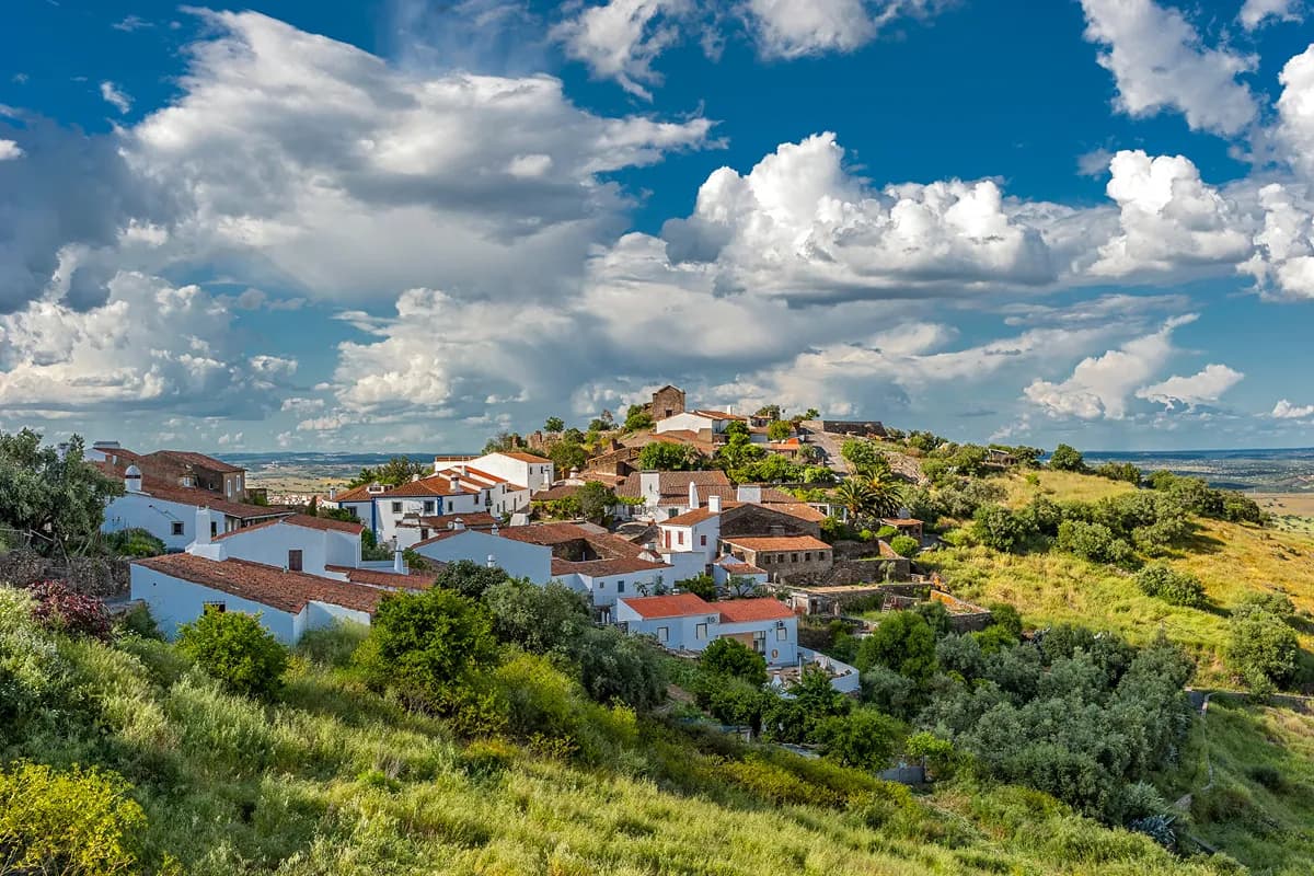 Whitewashed Alentejo village surrounded by green countryside under a blue sky