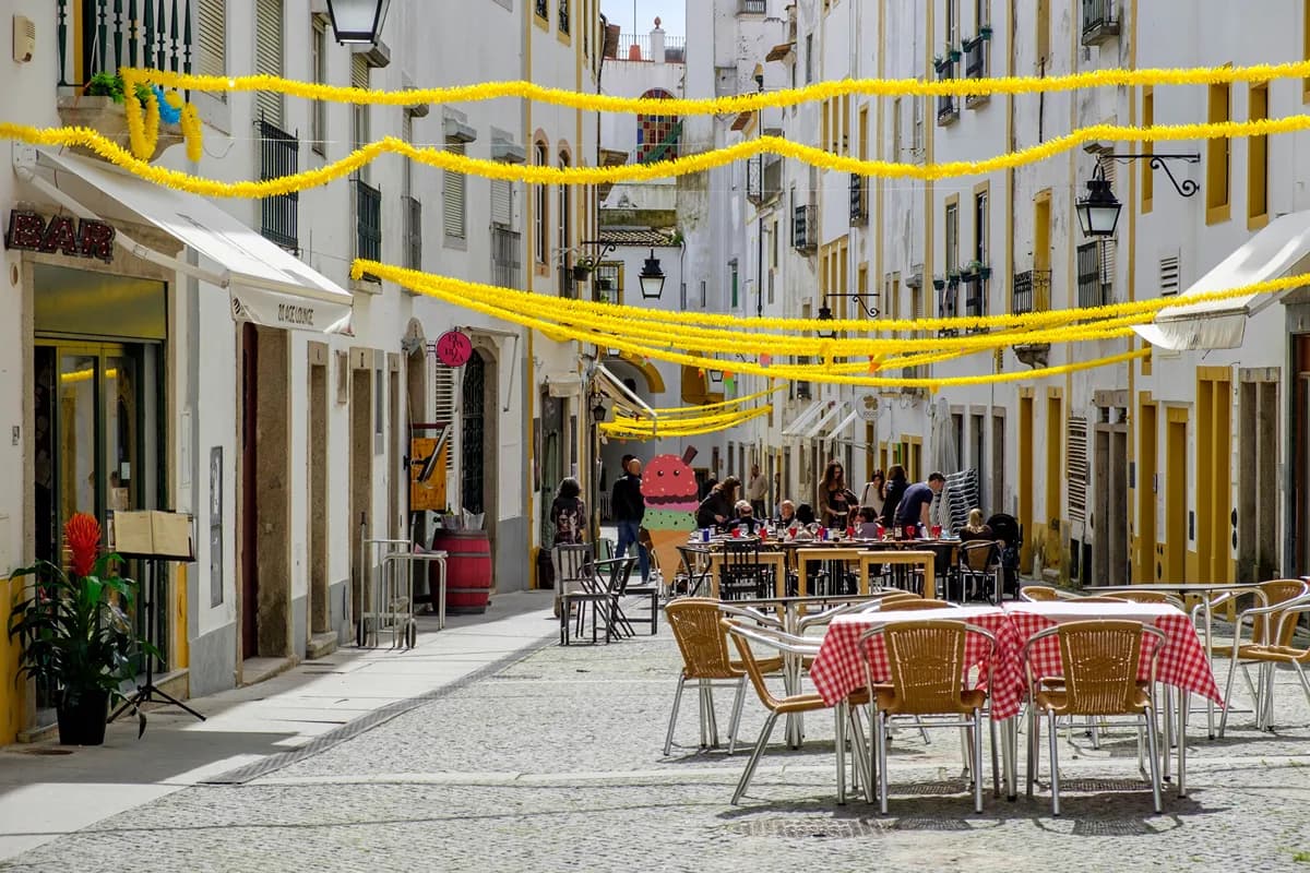 Pedestrian street with cafés, outdoor tables, and traditional white buildings in Évora