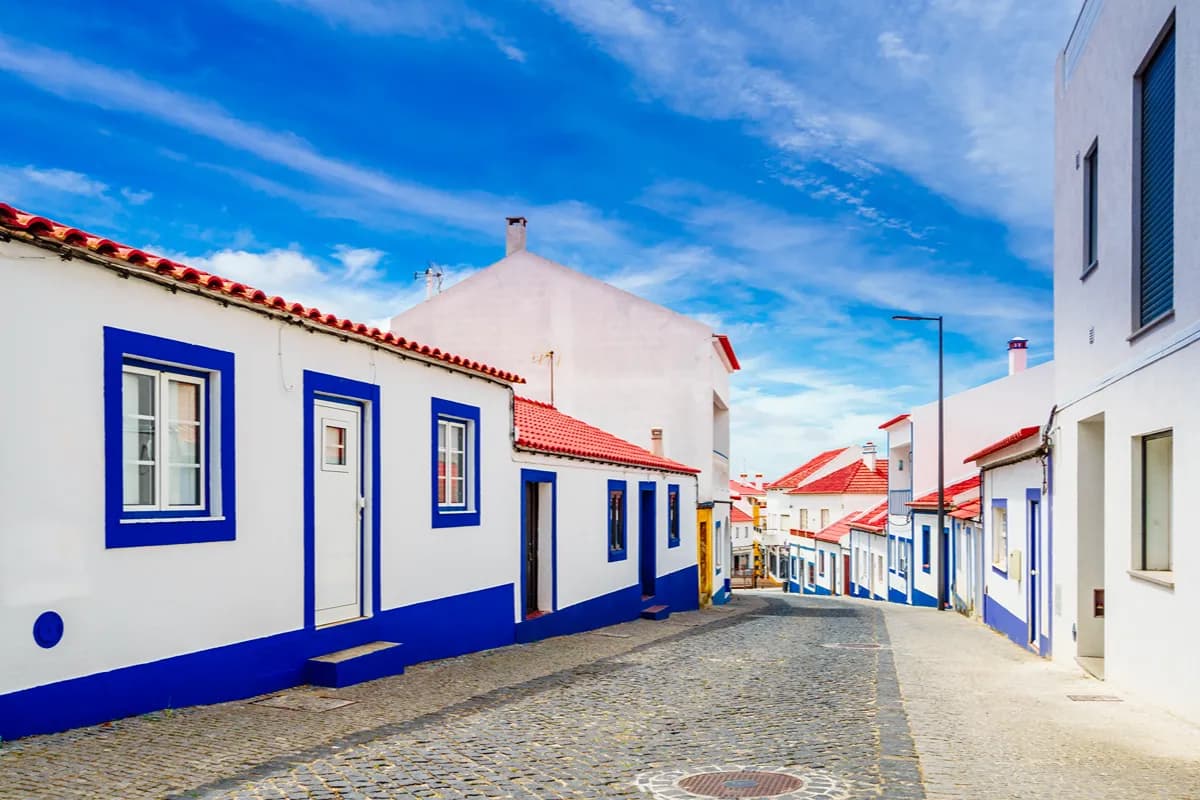 Quiet cobbled street lined with traditional white-and-blue houses in Vila Nova de Milfontes in the Alentejo
