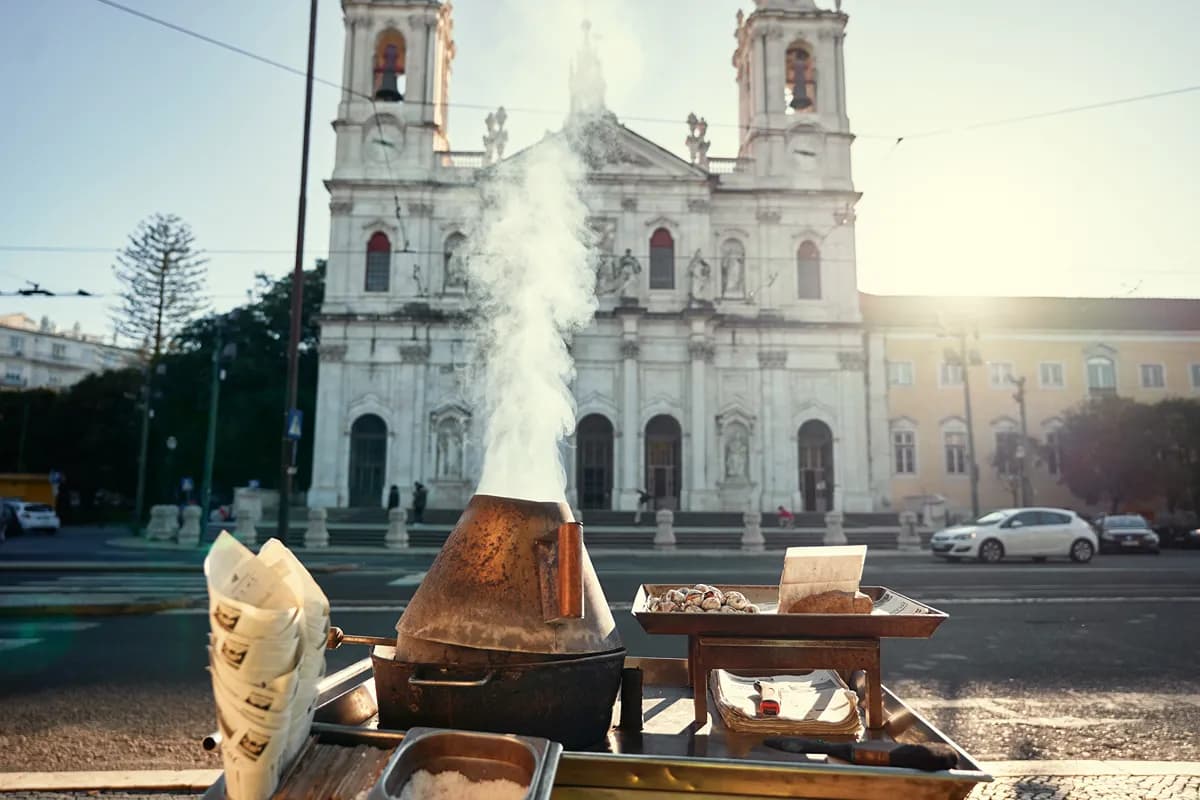 Roasted chestnuts sold in paper cones at a Portuguese street stall during autumn.