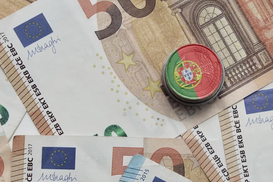 A range of Euro coins and notes, with the Portuguese flag