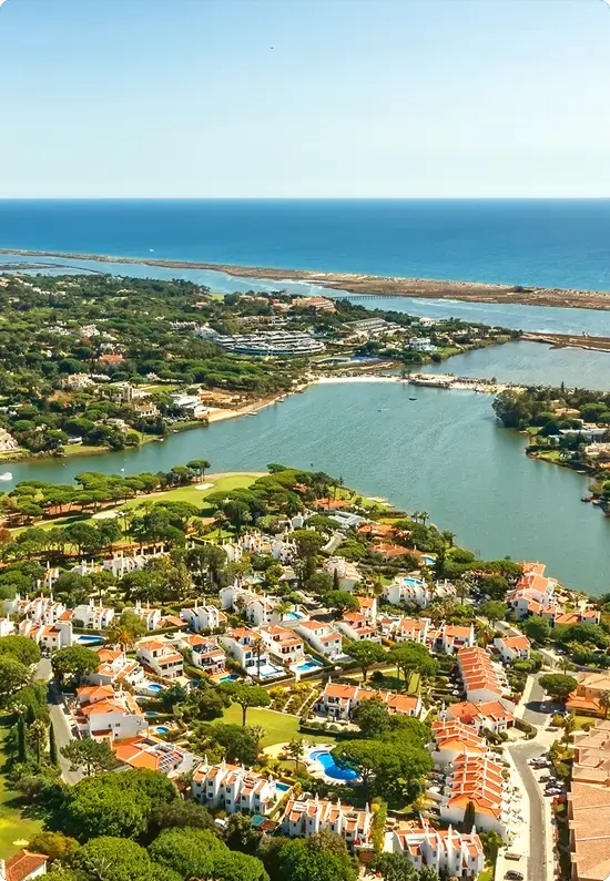 Aerial view of the Algarve's Ria Formosa with lagoons, greenery and red-roofed homes by the Atlantic Ocean