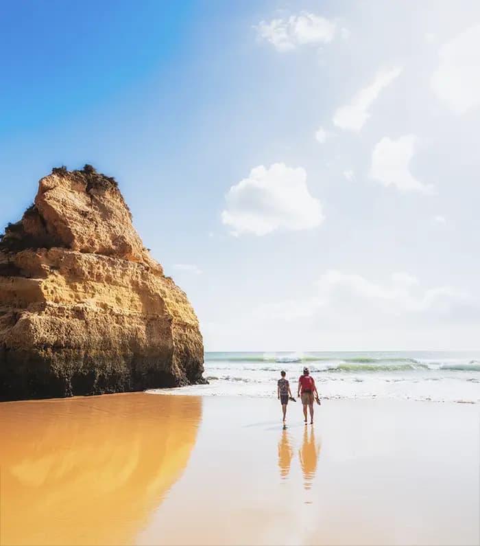 Couple walking on the beach close to a cliff in the Algarve