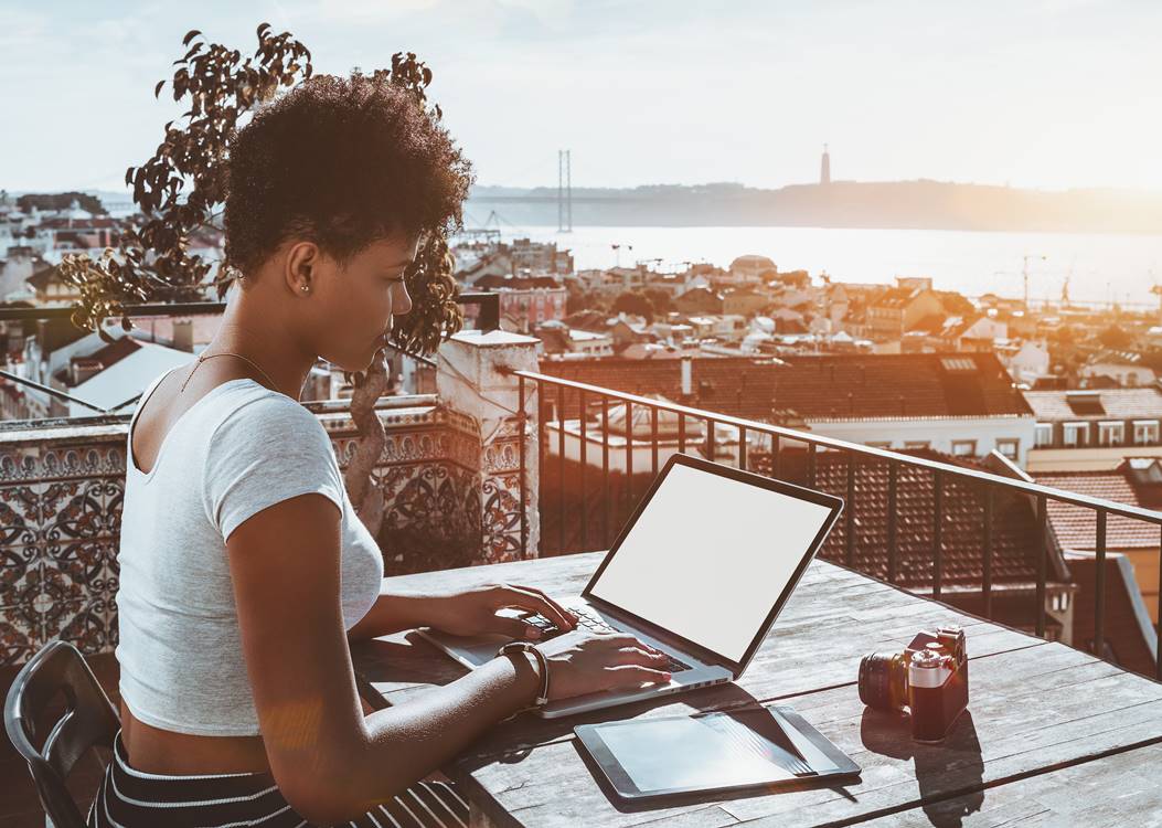 Lady working remotely while having a landscape view at Lisbon's bridge.